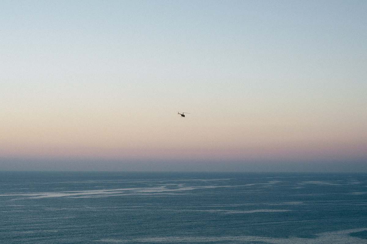 grey photo of helicopter hovering above body of water torrey pines state reserve